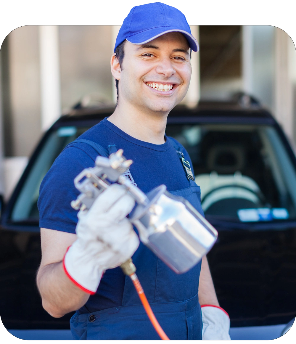 Car body repairer holding a spray gun